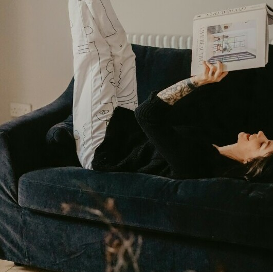 Lady lying on a couch with legs raised reading a magazine