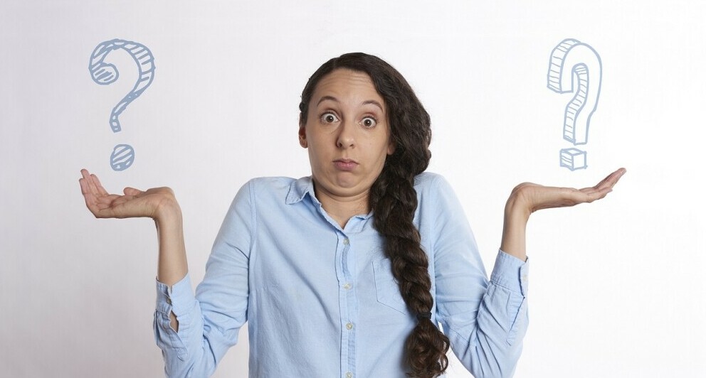 Woman with lifted arms in the I don't know gesture and 2 drawings of a question mark in each hand