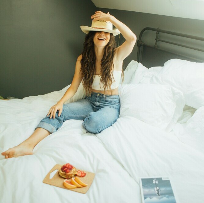 Girl sitting on a bed with a hat and smiling