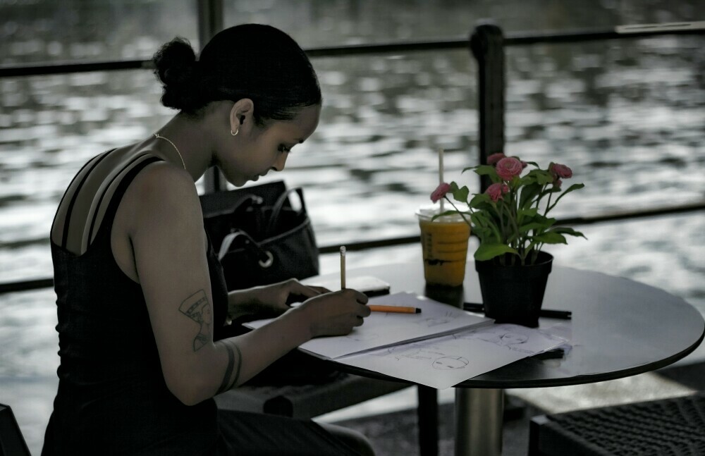 Girl sitting by a table by herself and writing 