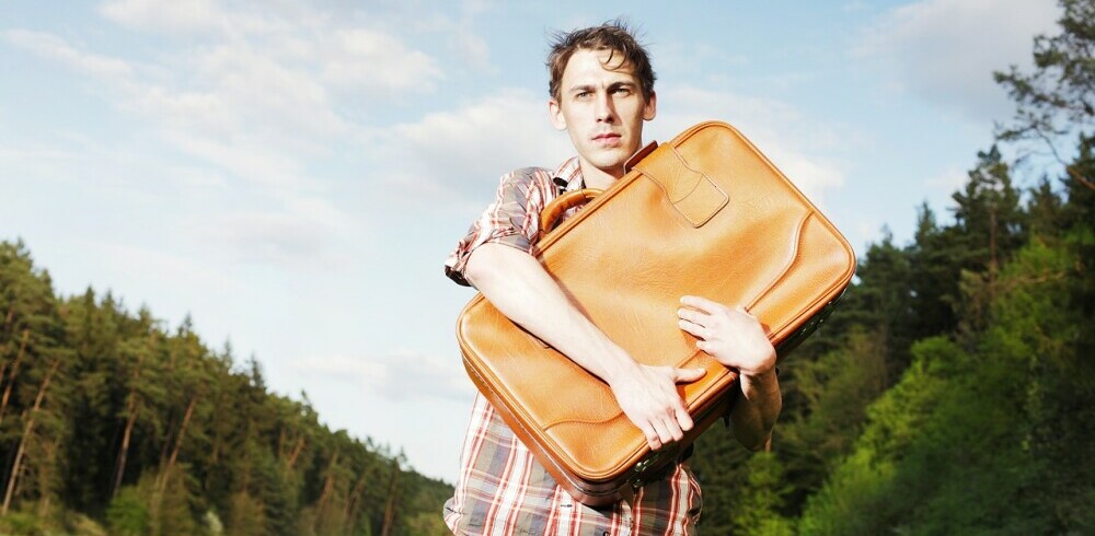 Man carrying a suitcase in a hugging way