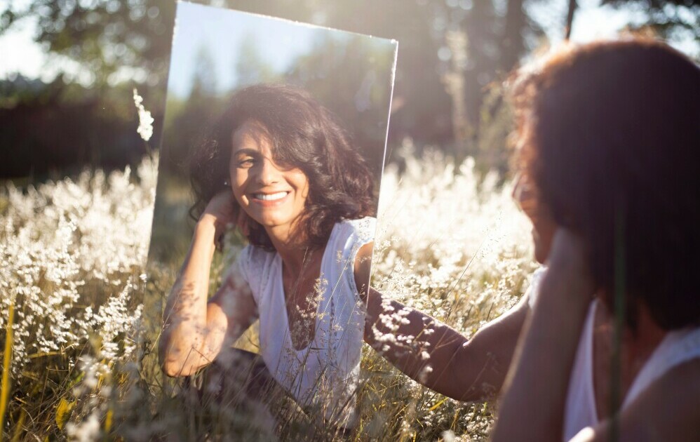 Girl looking at her reflection in the mirror smiling
