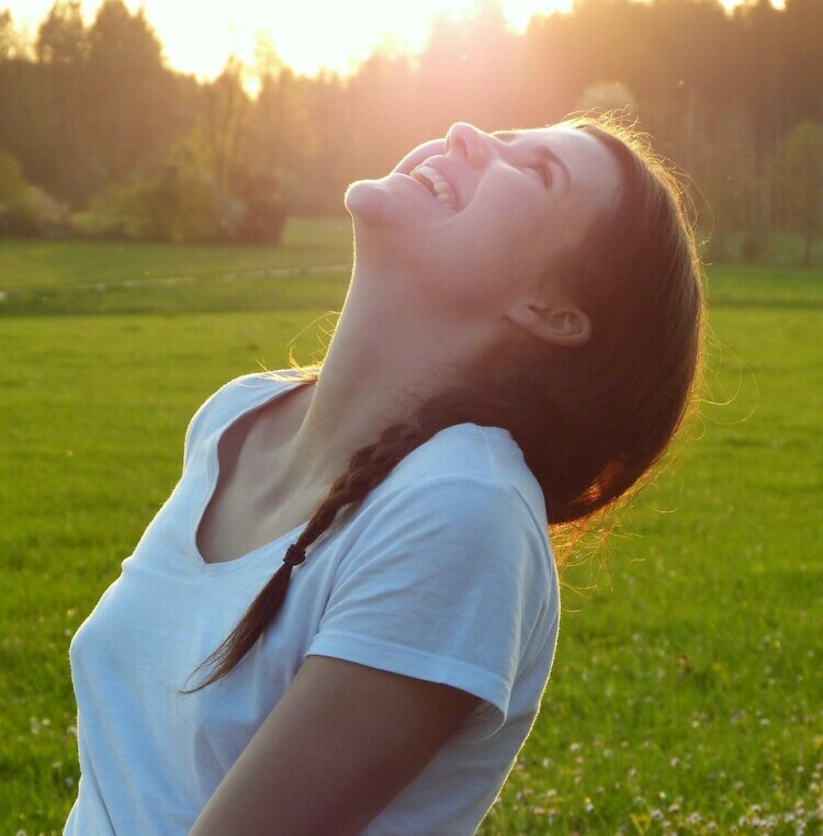 Girl looking up to the skies laughing 