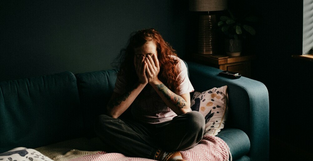 A girl sitting on a couch with face in hand