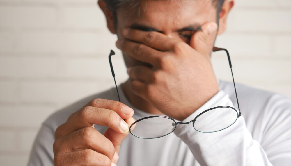 Person with glasses removed wiping eyes and possibly having a rough day