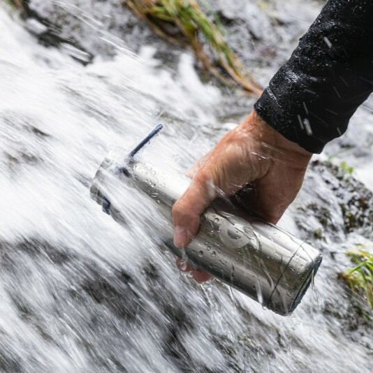 stainless steel bottle being refilled from a waterfall