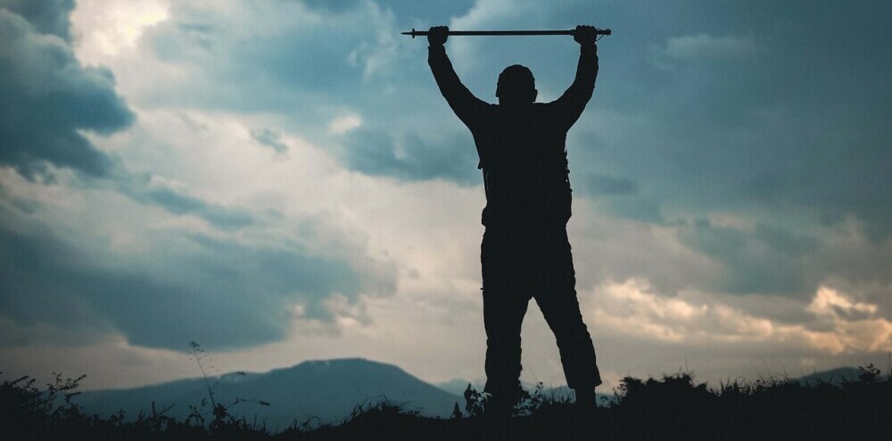 Man holding Trekking pole over his head in victory