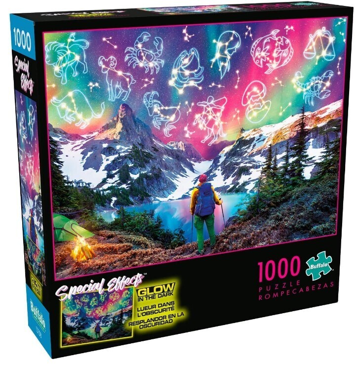 hiker with mountains and lake in the foreground and glow in the dark constellations in the sky