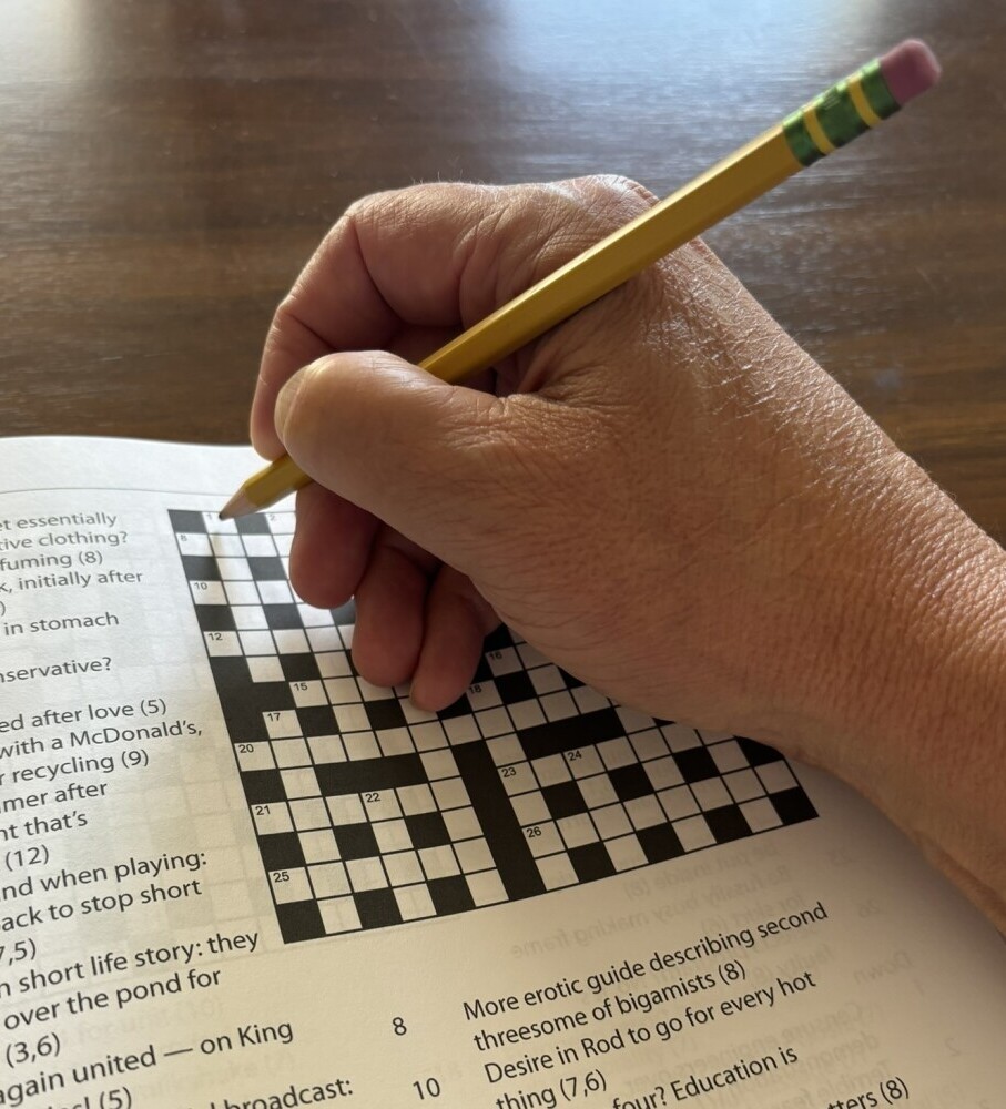 picture of hand with pencil about to solve an easy cryptic crosswords