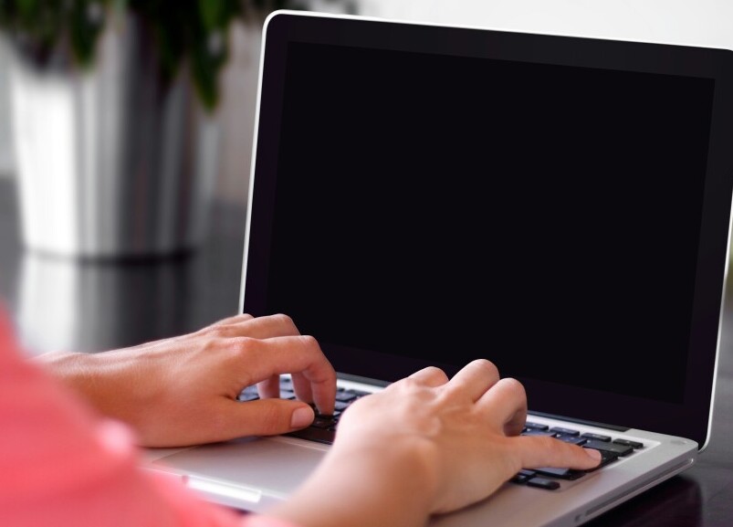 Image of laptop computer with woman's hands typing