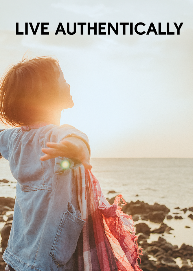 A young woman with shoulder-length hair stands on a rocky beach with her arms outstretched, facing the ocean and the setting sun, radiating joy and freedom.