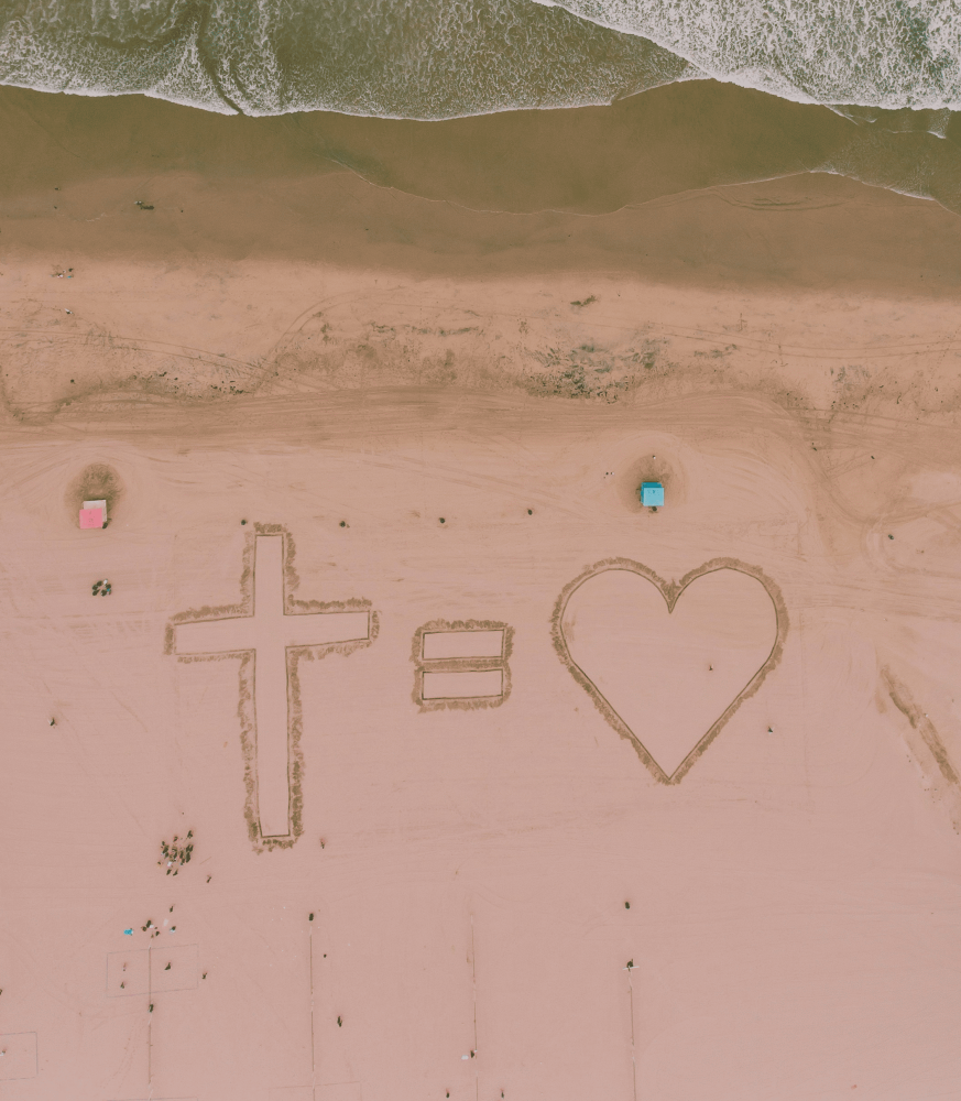 a cross equals love, which represents the meaning of the cross, drawn in symbols in the sand at the beach