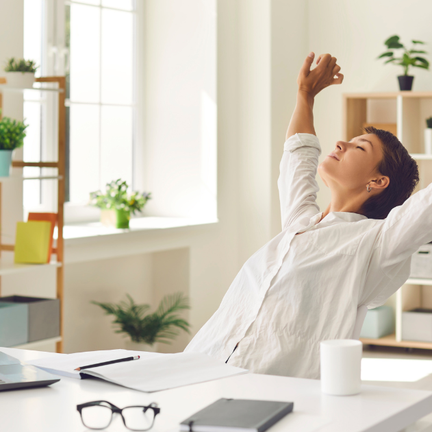A woman stretching at her desk to break up long sitting periods, improving circulation and reducing stiffness.