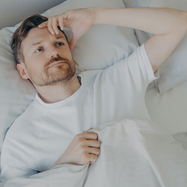 Frustrated person lying awake in bed, struggling with insomnia.