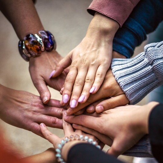 Sense of community. Many hands touching each other, showing support.