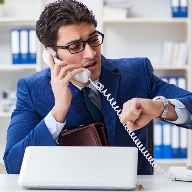 A stressed man, ending a call, looking at his watch, late for his next meeting.
