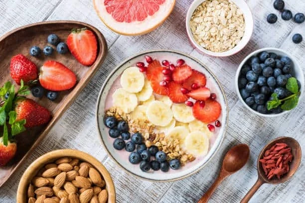 Healthy snack platter with yogurt, fresh berries, banana slices, oats, almonds, and nutritious toppings for busy families.