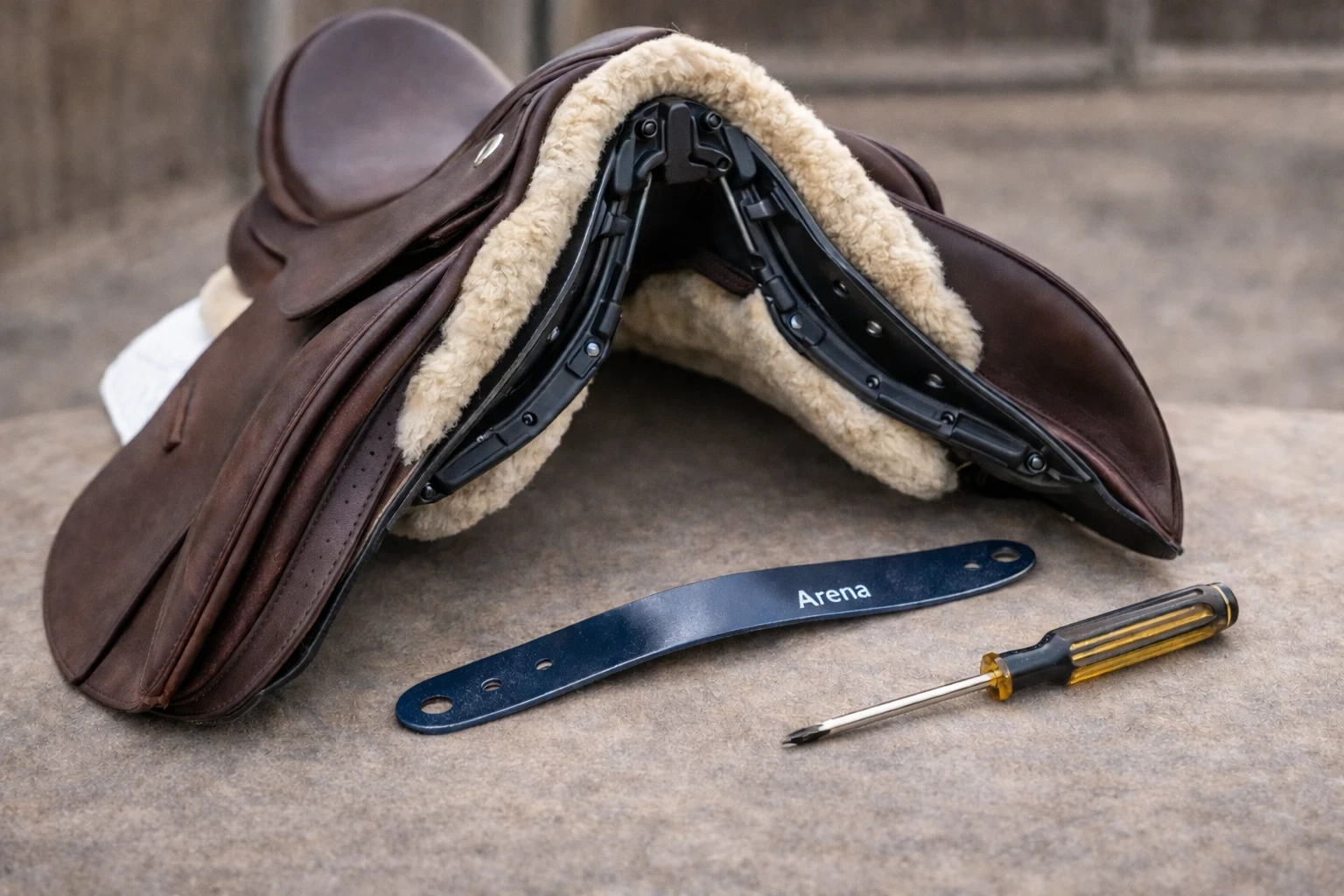 Close-up of dressage saddle with adjustable gullet plate removed showing changeable tree system and fitting tool