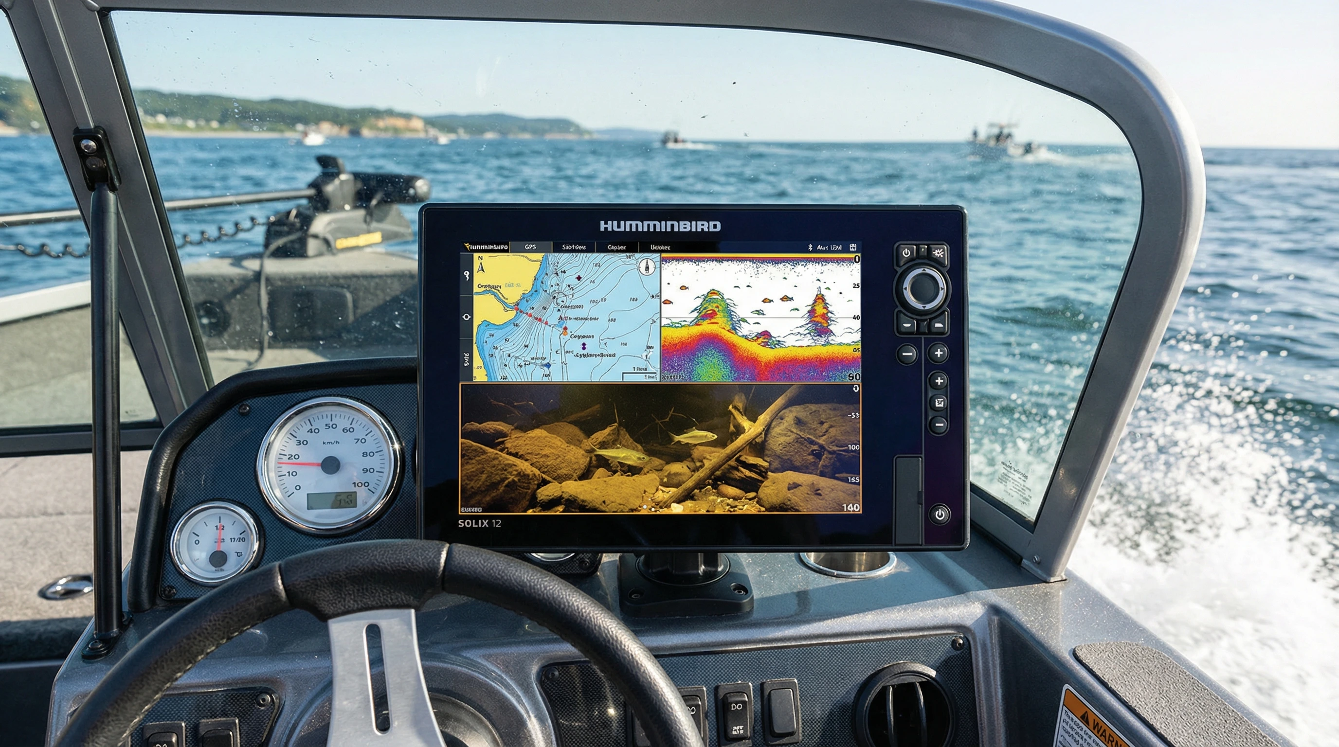 A modern fishfinder and chartplotter combo on a fishing boat, displaying underwater structure, GPS mapping, and a detailed side imaging sonar view. The device sits on the dashboard with the water visible in the background.