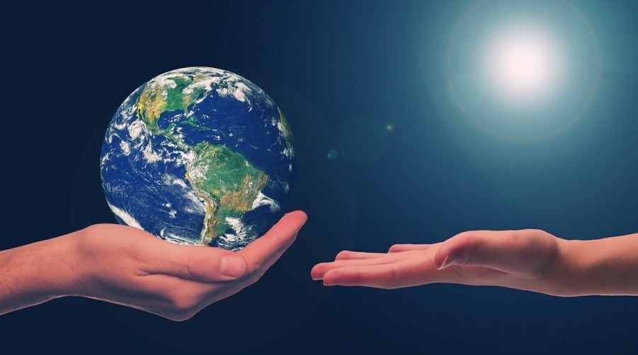 A hand holding onto earth passing to another hand