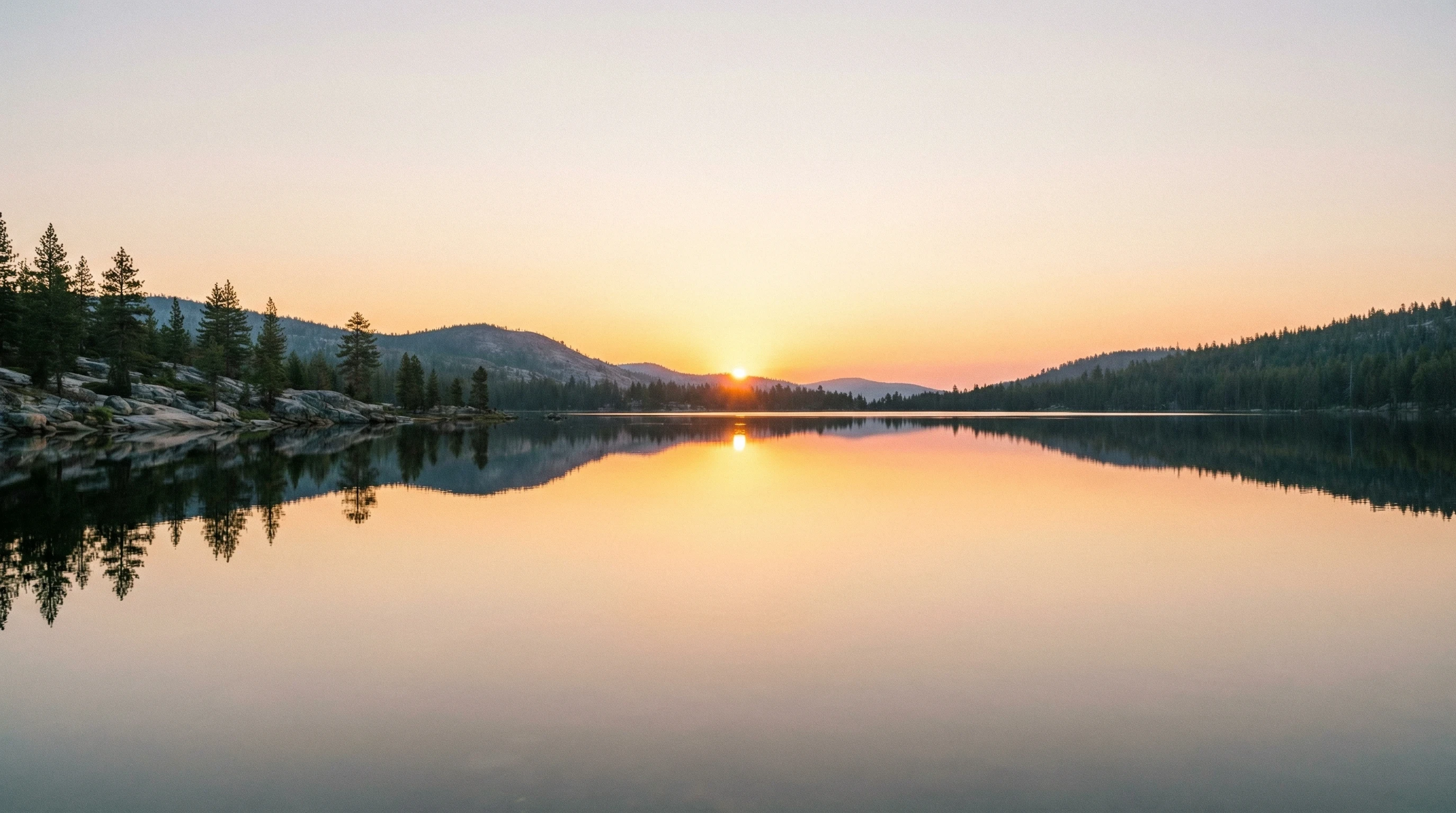 serene sunset over a calm alpine lake, with the sun's orange glow reflecting perfectly on the mirror-like water, surrounded by pine trees and rocky mountains.