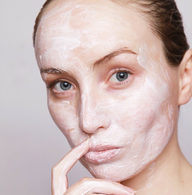 a woman applying some cream on her face