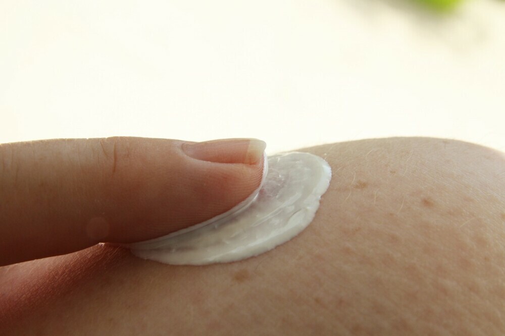 a woman applying a cream on her skin